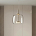 Brass pendant light with a clear bell shade, LED disc glowing softly warm white, BO-HA Astrid