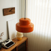 Orange Sunna pendant light above a teak console with a vintage typewriter and wall clock, styled in a mid-century Bauhaus corner